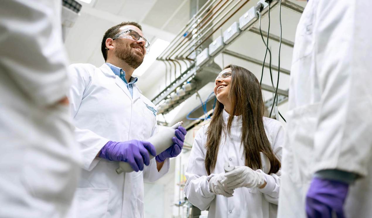 cinclus pharma man and woman in focus in group of scientists talking in a circle